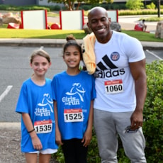 Two smiling Girls on the Run participants with a dad of participant